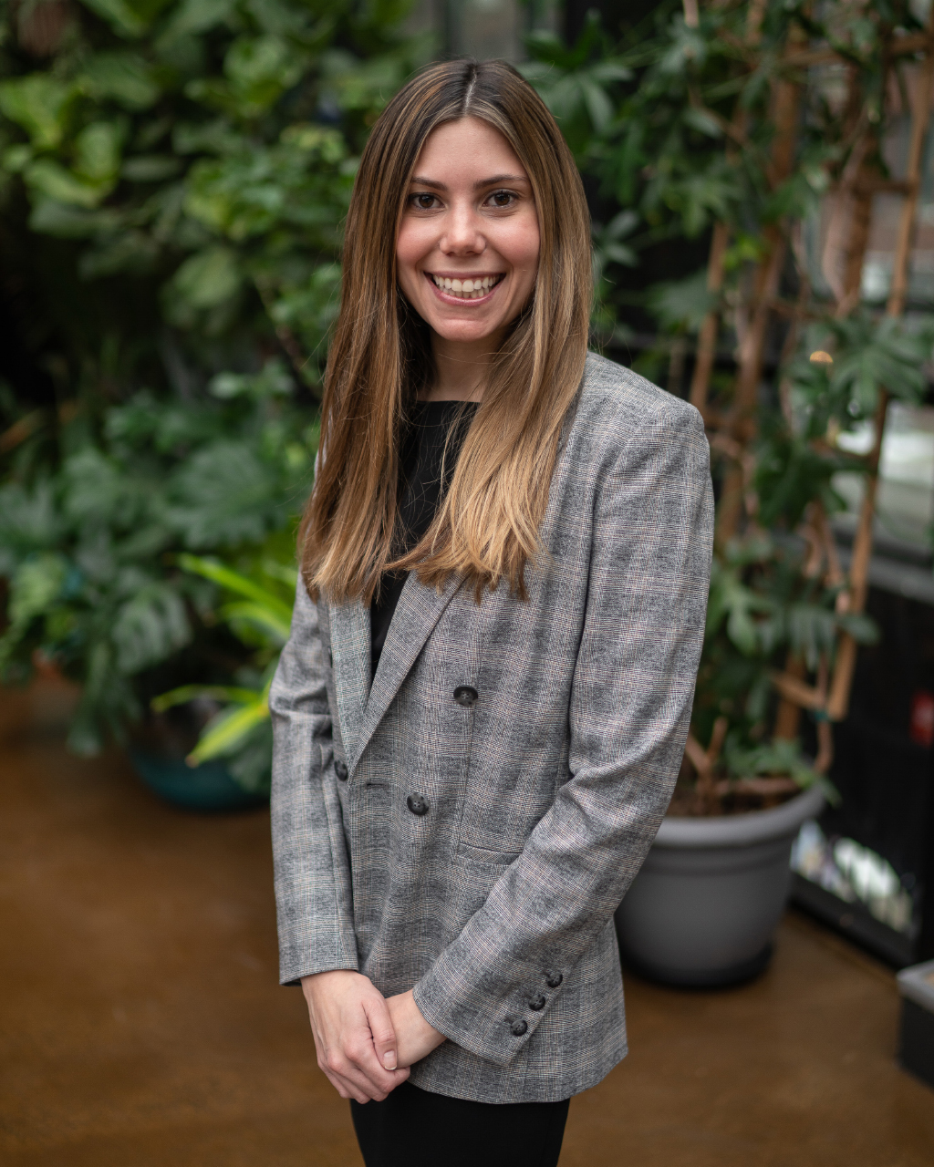 Photo of Danielle standing in front of plants in a well-lit area